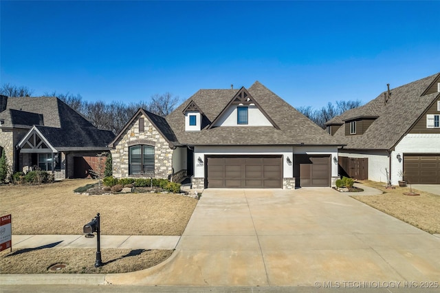 view of front of house featuring a garage, stone siding, roof with shingles, and driveway