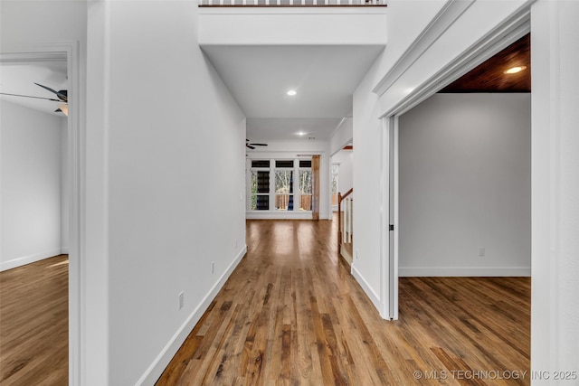 hallway featuring recessed lighting, wood finished floors, and baseboards