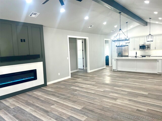 unfurnished living room with vaulted ceiling with beams, ceiling fan, and light hardwood / wood-style flooring