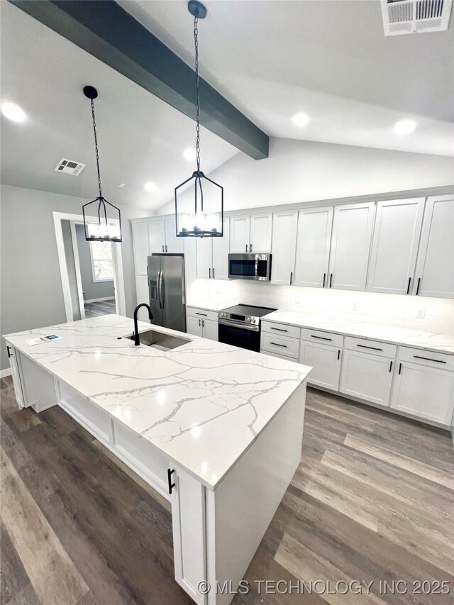 kitchen featuring hanging light fixtures, light stone countertops, stainless steel appliances, and a kitchen island with sink