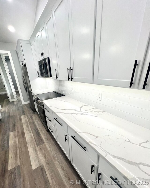 kitchen with backsplash, white cabinets, dark hardwood / wood-style floors, light stone counters, and stainless steel appliances