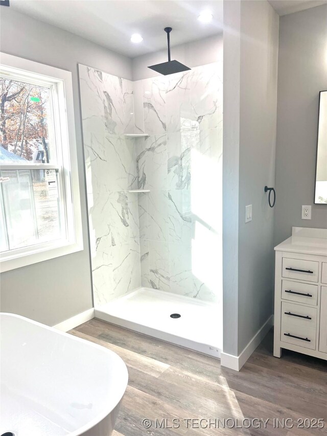 bathroom with hardwood / wood-style floors, vanity, and tiled shower