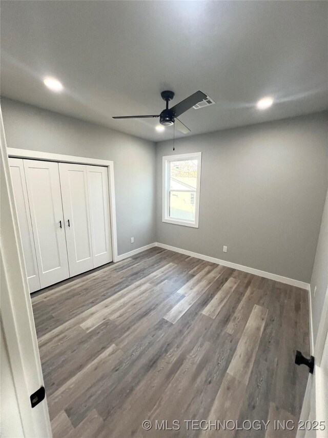 unfurnished bedroom with wood-type flooring, a closet, and ceiling fan