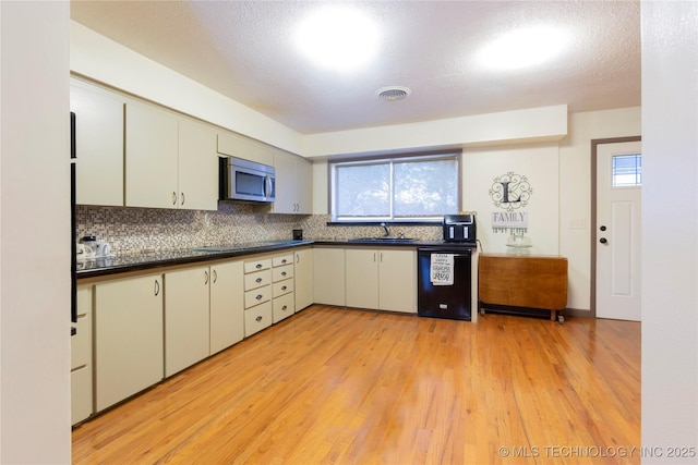 kitchen featuring a wealth of natural light, sink, black appliances, and light wood-type flooring