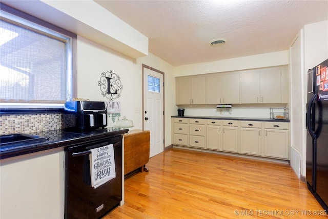 kitchen with light wood-type flooring, backsplash, a textured ceiling, sink, and black appliances