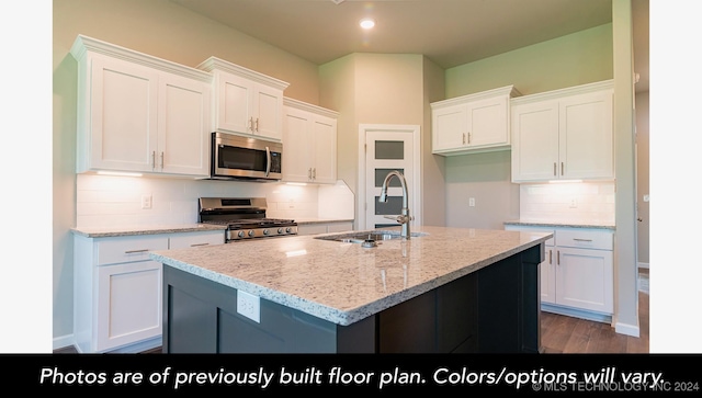 kitchen featuring appliances with stainless steel finishes, white cabinetry, a kitchen island with sink, and sink