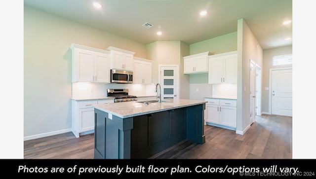 kitchen featuring light stone countertops, appliances with stainless steel finishes, sink, a center island with sink, and white cabinets