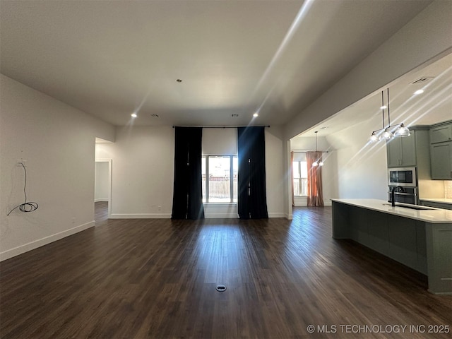 unfurnished living room featuring sink and dark wood-type flooring