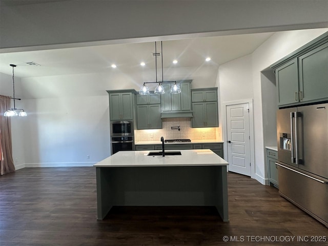 kitchen with tasteful backsplash, stainless steel appliances, hanging light fixtures, and an island with sink