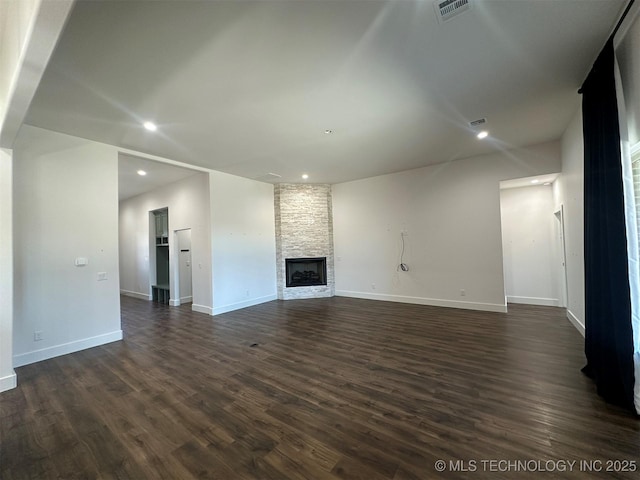 unfurnished living room with a stone fireplace and dark wood-type flooring