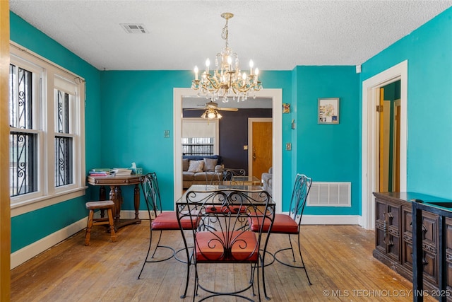 dining area featuring hardwood / wood-style floors, ceiling fan with notable chandelier, and a textured ceiling