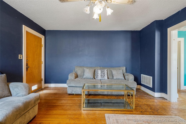 living room with wood-type flooring, a textured ceiling, and ceiling fan