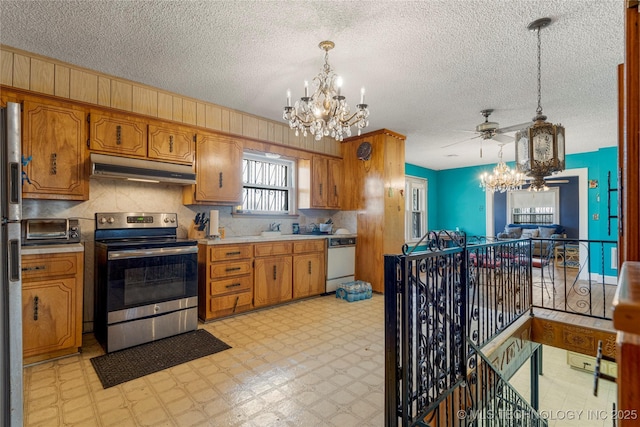 kitchen featuring pendant lighting, ceiling fan with notable chandelier, stainless steel appliances, and a textured ceiling