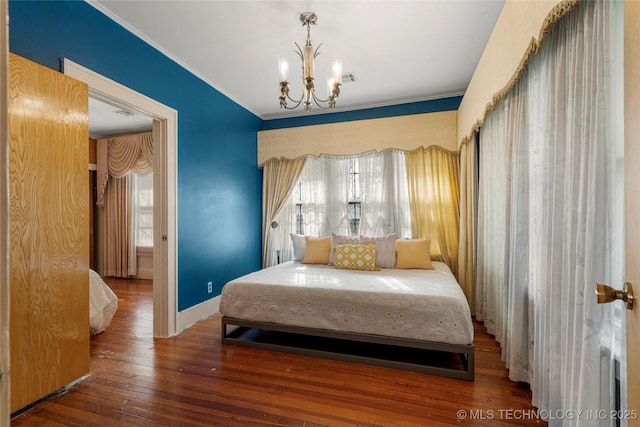 bedroom featuring hardwood / wood-style floors, an inviting chandelier, and ornamental molding