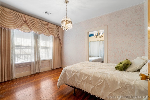 bedroom with wood-type flooring and a notable chandelier