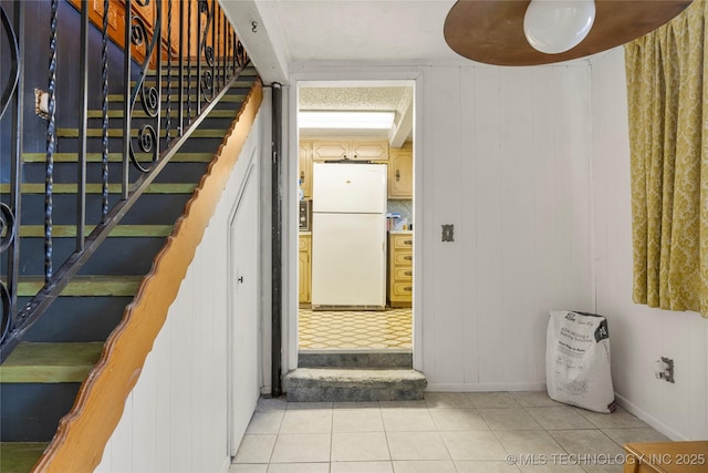 stairway featuring tile patterned floors and wood walls