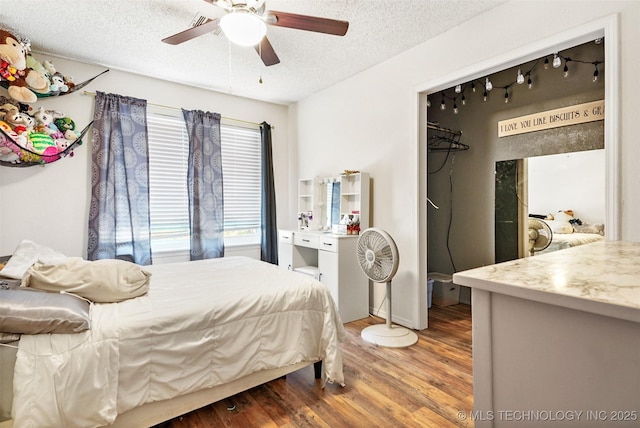 bedroom with hardwood / wood-style floors, ceiling fan, and a textured ceiling