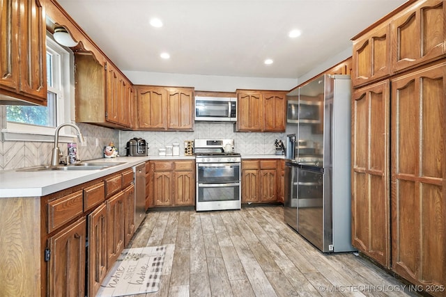 kitchen featuring tasteful backsplash, sink, light hardwood / wood-style flooring, and appliances with stainless steel finishes