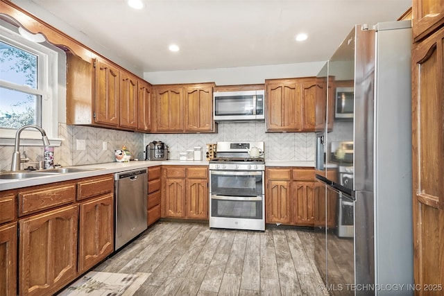 kitchen with backsplash, stainless steel appliances, light hardwood / wood-style floors, and sink