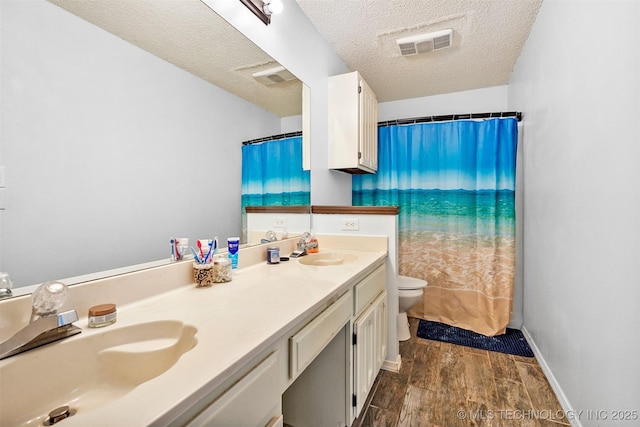 bathroom with a shower with curtain, vanity, a textured ceiling, and toilet