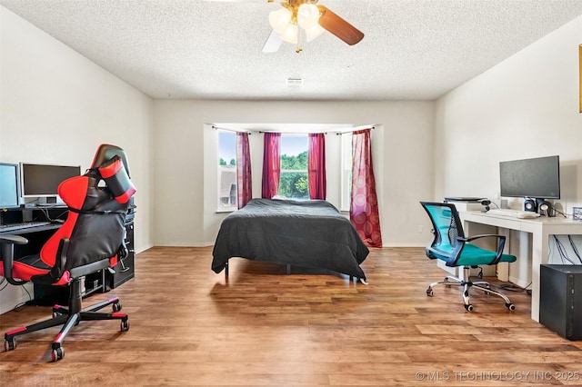 bedroom with light wood-type flooring, a textured ceiling, and ceiling fan