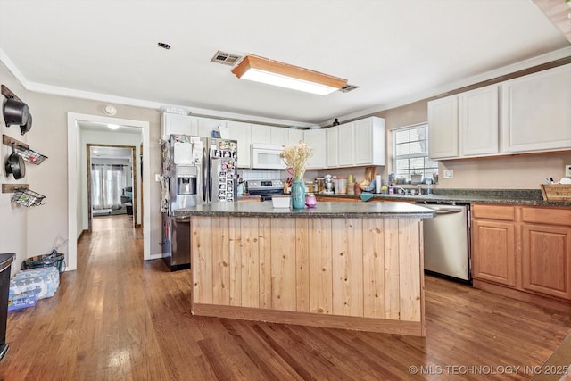 kitchen with light wood-type flooring, stainless steel appliances, a kitchen island, and tasteful backsplash