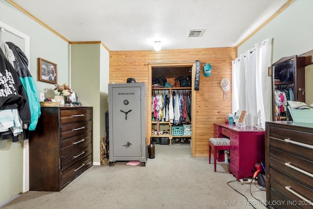 carpeted bedroom with a closet, wood walls, and crown molding