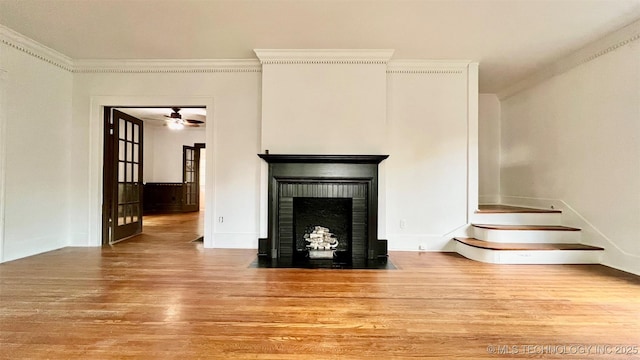 unfurnished living room with a fireplace, light wood-type flooring, ceiling fan, and ornamental molding