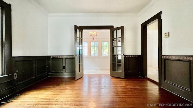 unfurnished room with hardwood / wood-style floors, ornamental molding, french doors, and a chandelier