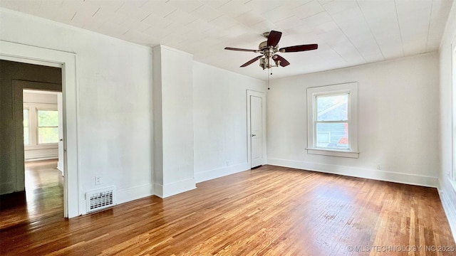 empty room with hardwood / wood-style flooring, ceiling fan, and plenty of natural light