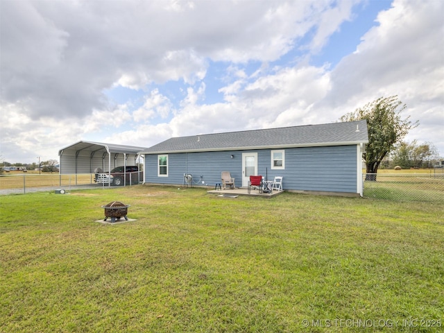 back of property with a carport, an outdoor fire pit, and a lawn