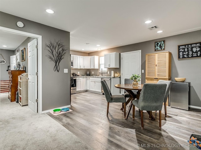 dining space with light hardwood / wood-style flooring and sink