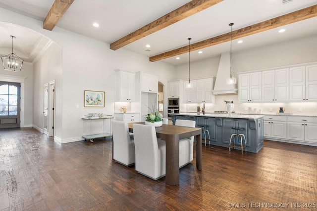 3913 S Dogwood Blvd, Broken Arrow, OK 74012 - kitchen featuring an island with sink, custom range hood, a breakfast bar, decorative light fixtures, and white cabinetry