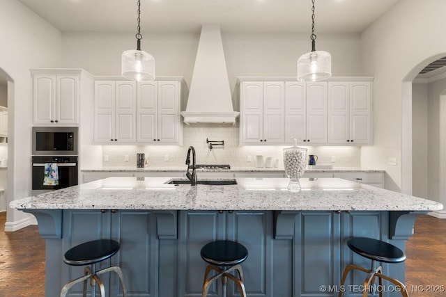 3913 S Dogwood Blvd, Broken Arrow, OK 74012 - kitchen featuring arched walkways, pendant lighting, white cabinetry, stainless steel oven, and premium range hood