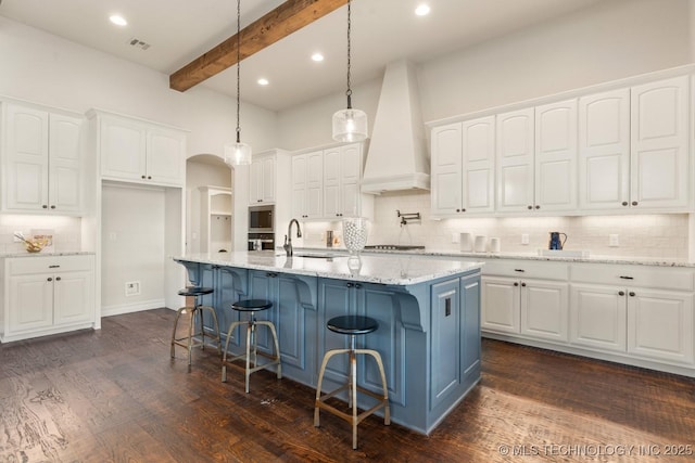 3913 S Dogwood Blvd, Broken Arrow, OK 74012 - kitchen with a kitchen island with sink, custom range hood, arched walkways, and white cabinets