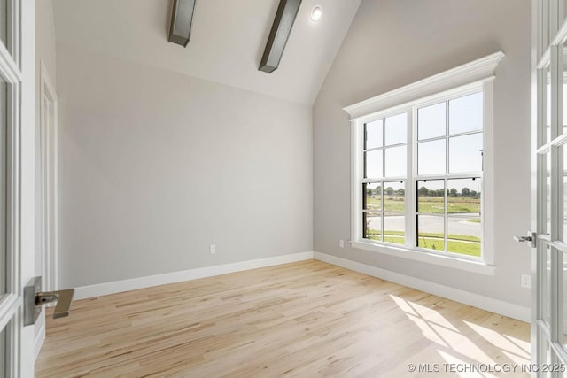 unfurnished room featuring a healthy amount of sunlight, light wood-type flooring, and vaulted ceiling