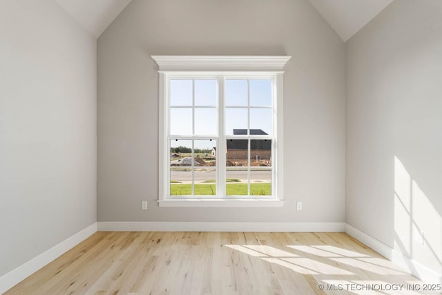 spare room with light hardwood / wood-style flooring and vaulted ceiling