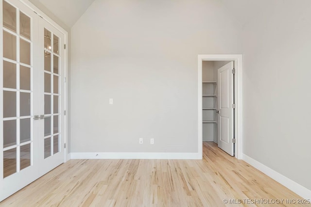 unfurnished room with french doors, light hardwood / wood-style flooring, and vaulted ceiling