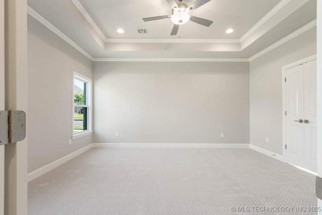 unfurnished room with light colored carpet, ceiling fan, and a tray ceiling