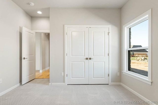 unfurnished bedroom featuring light colored carpet, multiple windows, and a closet