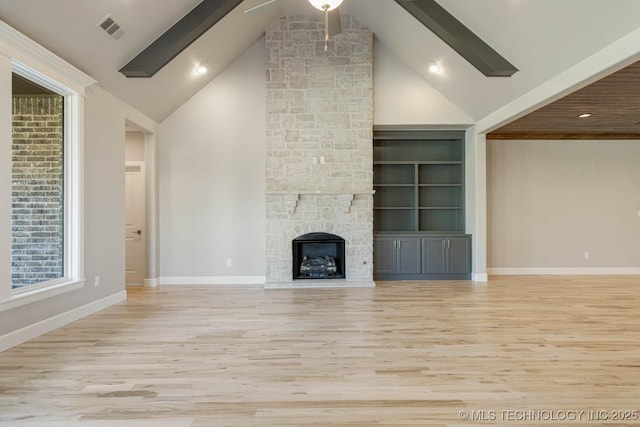 unfurnished living room with built in shelves, a fireplace, light hardwood / wood-style floors, and vaulted ceiling with beams