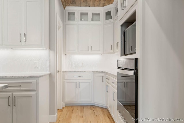 kitchen with stainless steel oven, white cabinets, wood ceiling, and light wood-type flooring