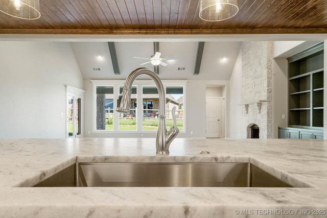 kitchen with built in shelves, a fireplace, lofted ceiling with beams, and sink