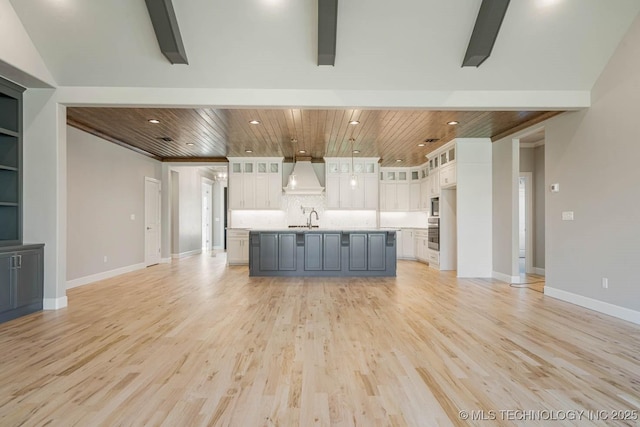 kitchen with sink, white cabinetry, an island with sink, and premium range hood