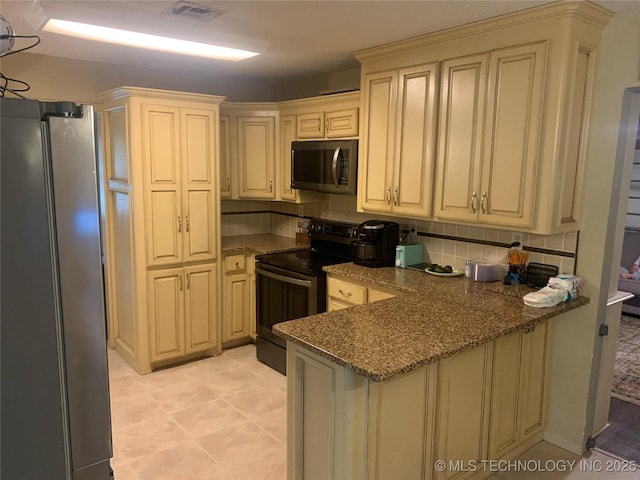 kitchen with black electric range, stainless steel fridge, kitchen peninsula, and dark stone countertops