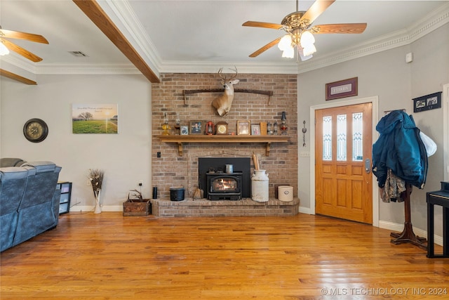 living room featuring light hardwood / wood-style flooring, a wood stove, and ornamental molding