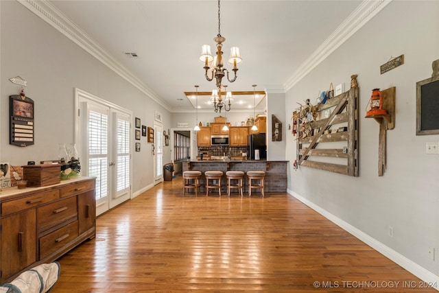 dining room featuring light wood-type flooring, crown molding, and a notable chandelier