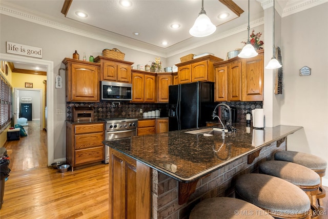 kitchen with kitchen peninsula, appliances with stainless steel finishes, a kitchen breakfast bar, sink, and pendant lighting