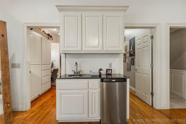 kitchen featuring white cabinets, refrigerator, light wood-type flooring, and sink