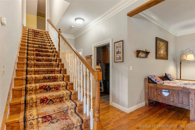 staircase with crown molding, a textured ceiling, and hardwood / wood-style flooring